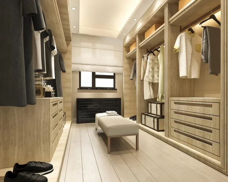 a walk-in closet with a bench and clothes on the shelves